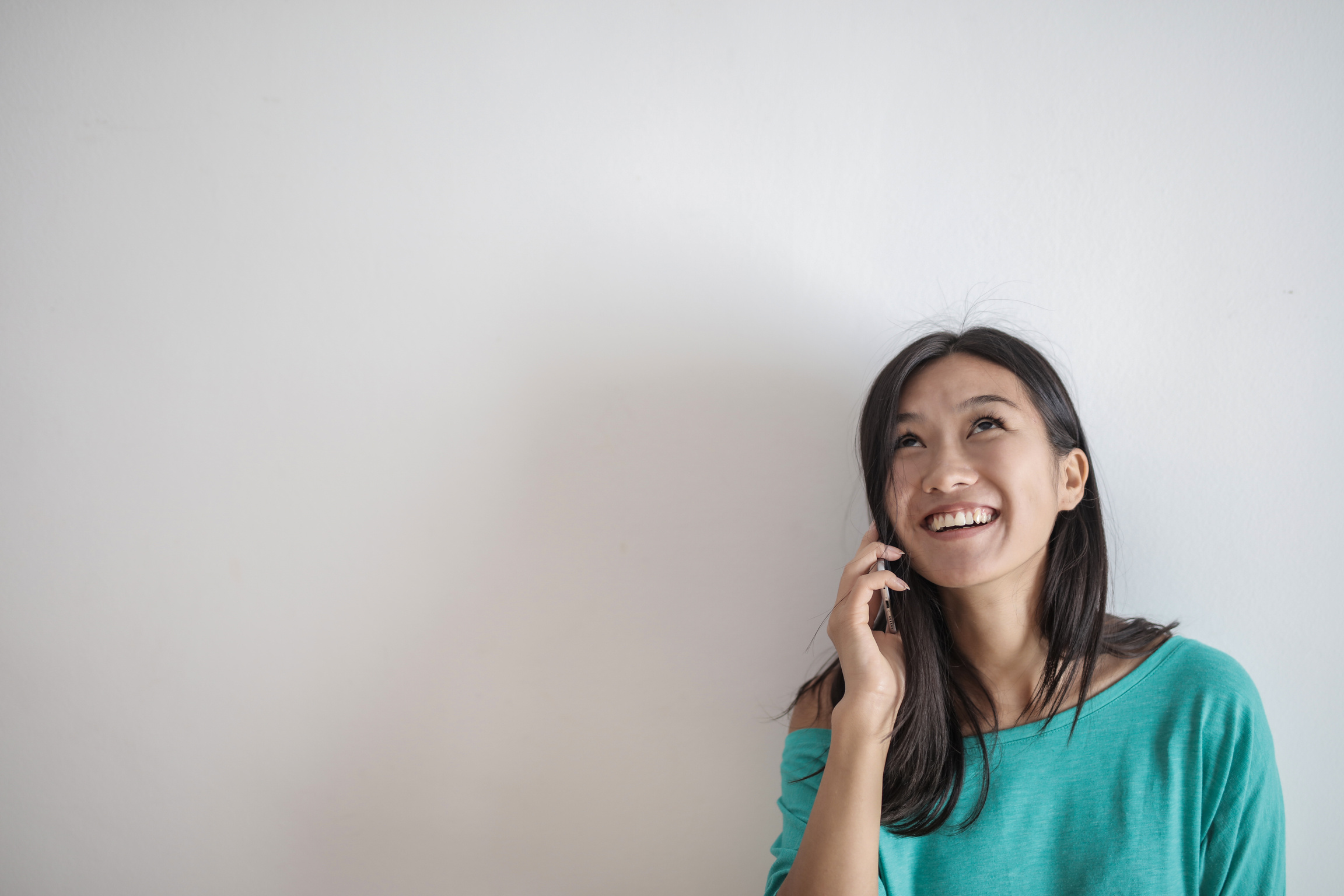 Portrait Photo of Smiling Woman in a Teal Top Talking on the Phone